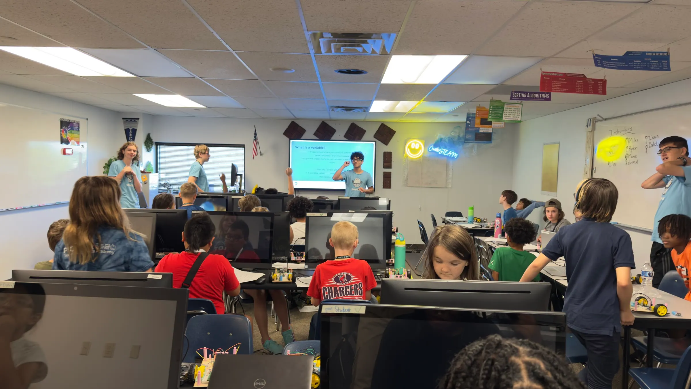 Students and Eaglets instructors work at computer stations during a robotics camp.