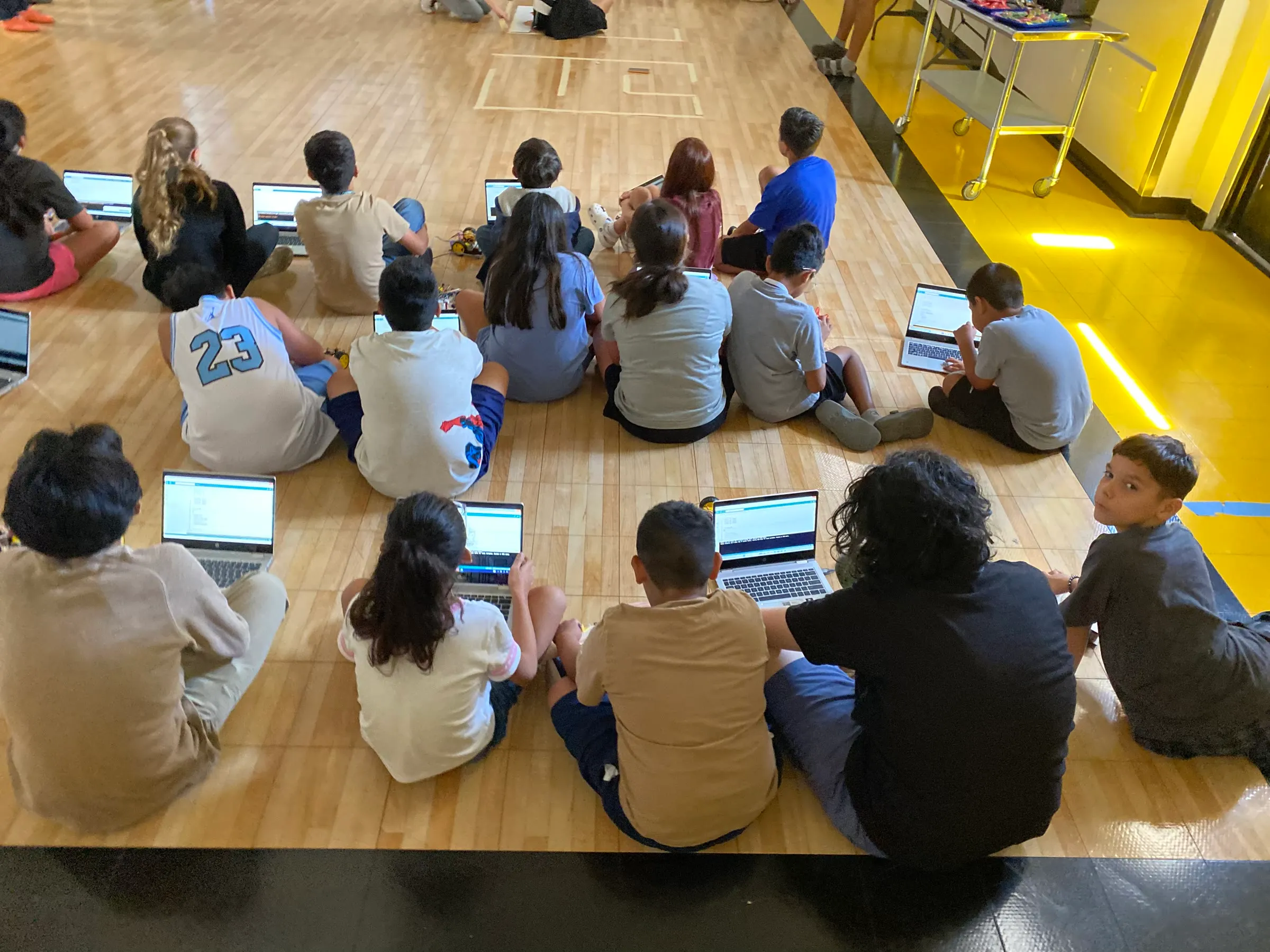 Students sit with laptops and robot kits while working through a programming activity.