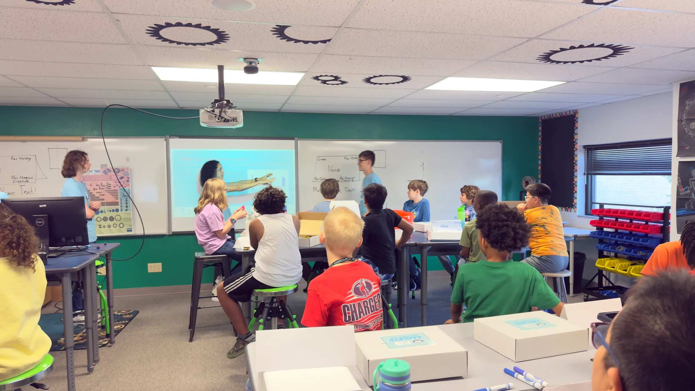 Eaglets instructors lead a classroom robotics activity while students work at tables.